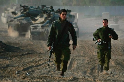 Israeli army officers run past a pair of tanks manoeuvring at their forward base on the border with the Gaza Strip on December 19, 2008 near Kibbutz Nahal Oz in southern Israel. A six-month ceasefire between Israel and the militant Islamist organization Hamas ended early this morning, with senior Israeli government officials warning that a military offensive in the Gaza Strip will be unavoidable if the rocket fire from the territory continues.  (Photo by David Silverman/Getty Images)
