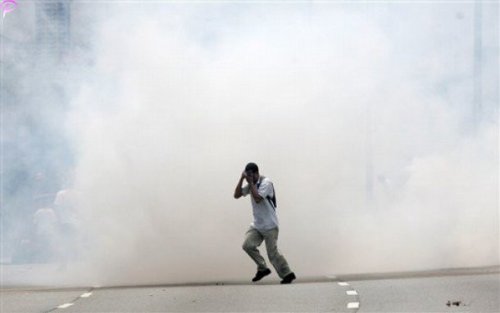 A protester covers himself as he runs away from tear gas fired by Malaysian riot police during a protest against using English for mathematics and science teaching in Kuala Lumpur, Malaysia, Saturday, March 7, 2009.AP Photo