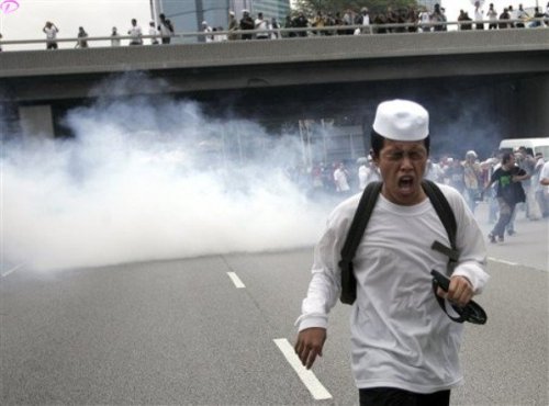 A protester runs away from tear gas fired by Malaysian riot police during a protest against  the use of English to teach math and science in Kuala Lumpur, Malaysia, Saturday, March 7, 2009.AP Photo