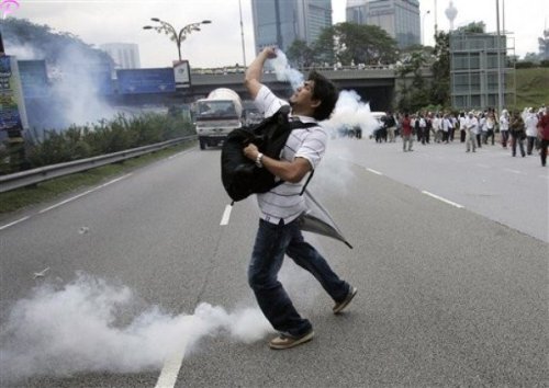 A protester throws back a tear gas which fired by riot police during a protest against using English for mathematics and science teaching in Kuala Lumpur, Malaysia, Saturday, March 7, 2009.AP Photo