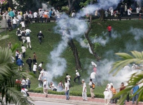 Protesters run away from tear gas fired by Malaysian riot police during a protest against the use of English to teach math and science  in Kuala Lumpur, Malaysia, Saturday, March 7, 2009. 